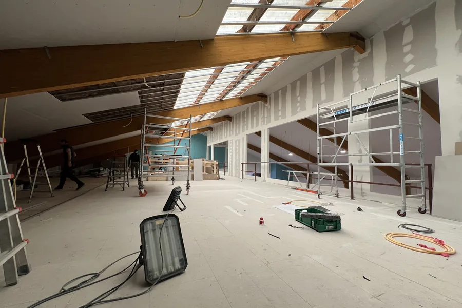 Kantoorpand in verbouwing met zichtbare dakconstructie en steigers, waar label C-maatregelen meelopen met een lopende renovatie